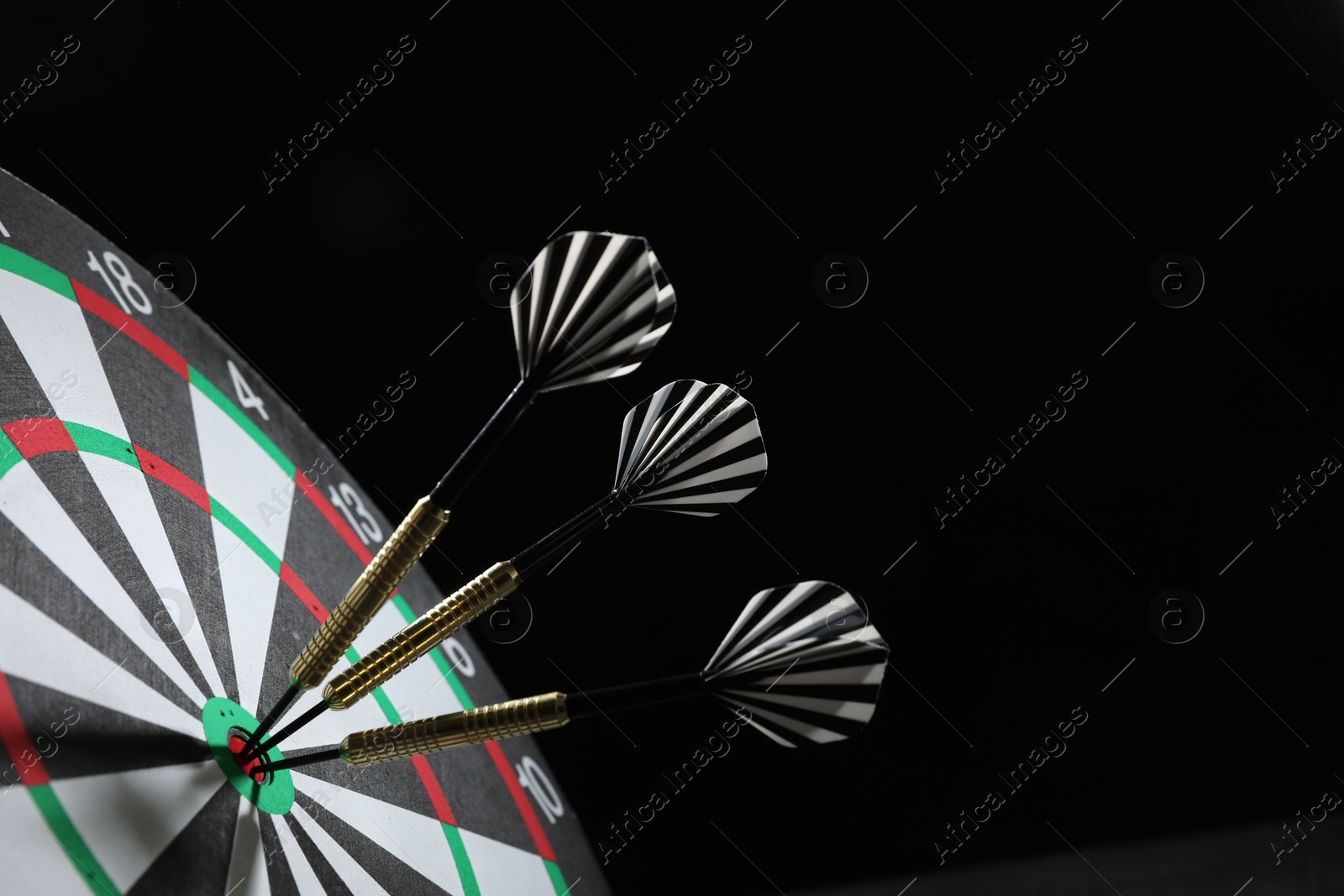 Targeting. Dart board with arrows on black background, closeup. Space for text Photo of Targeting. Dart board with arrows on black background, closeup. Space for text