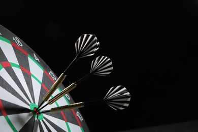Photo of Targeting. Dart board with arrows on black background, closeup. Space for text
