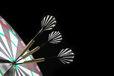 Photo of Targeting. Dart board with arrows on black background, closeup. Space for text