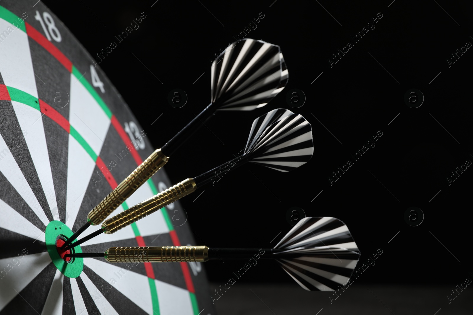 Targeting. Dart board with arrows on black background, closeup Photo of Targeting. Dart board with arrows on black background, closeup