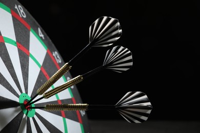 Photo of Targeting. Dart board with arrows on black background, closeup