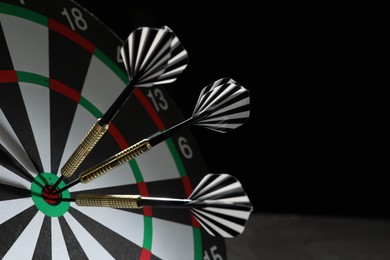 Photo of Targeting. Dart board with arrows on black background, closeup