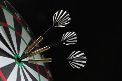 Photo of Targeting. Dart board with arrows on black background, closeup