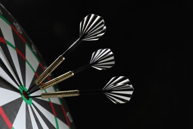 Photo of Targeting. Dart board with arrows on black background, closeup