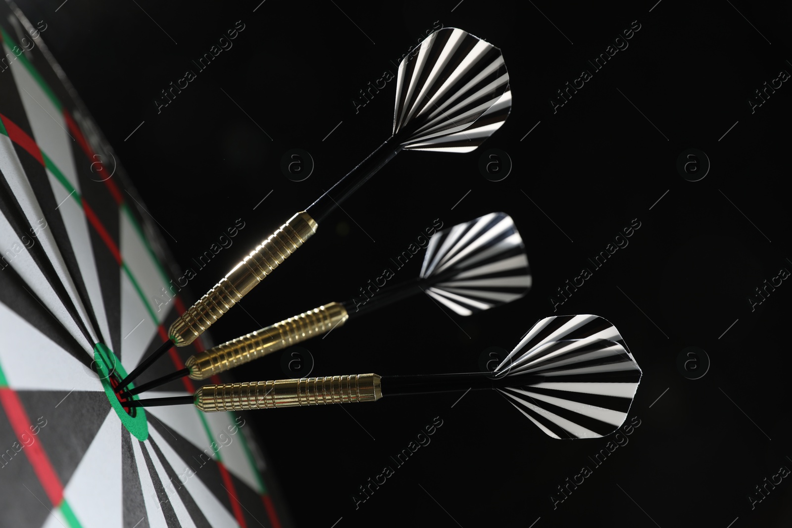 Targeting. Dart board with arrows on black background, closeup Photo of Targeting. Dart board with arrows on black background, closeup