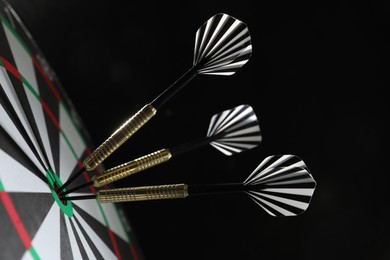 Photo of Targeting. Dart board with arrows on black background, closeup