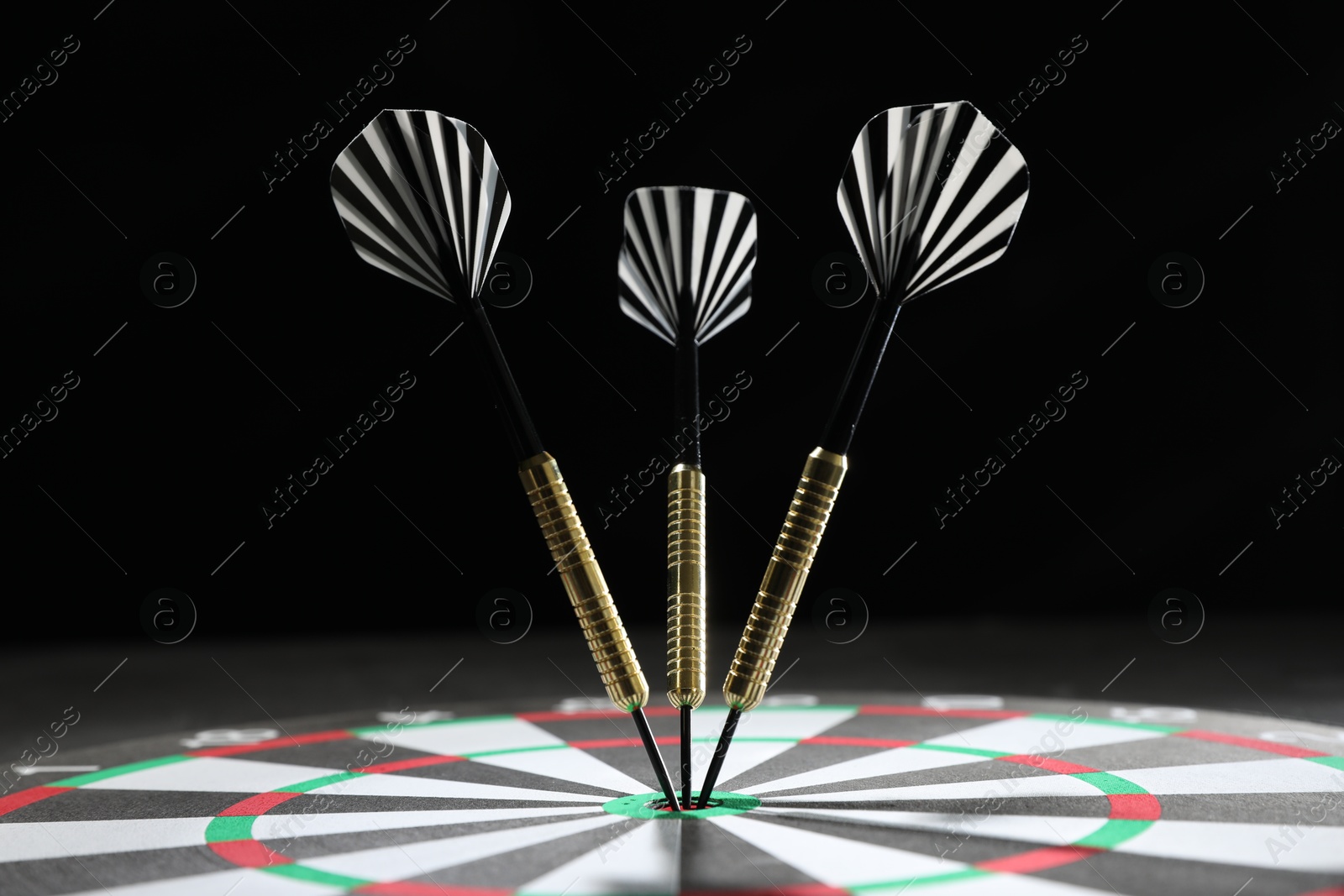 Targeting. Dart board with arrows against dark background, closeup Photo of Targeting. Dart board with arrows against dark background, closeup