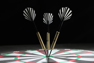 Photo of Targeting. Dart board with arrows against dark background, closeup