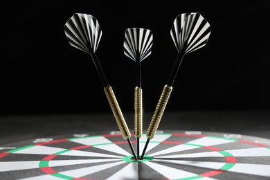 Photo of Targeting. Dart board with arrows against dark background, closeup