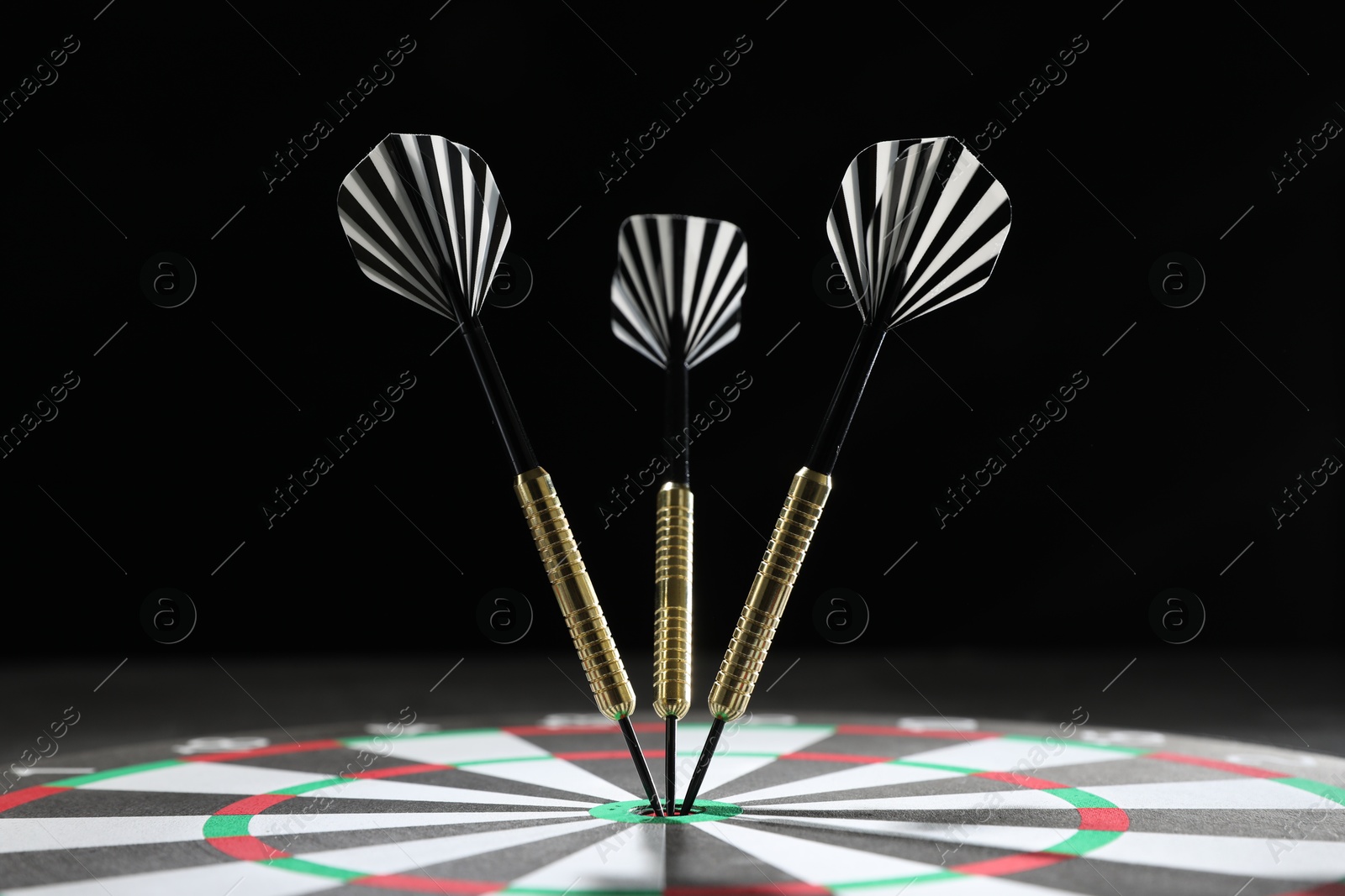 Targeting. Dart board with arrows against dark background, closeup Photo of Targeting. Dart board with arrows against dark background, closeup