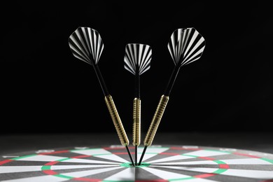 Photo of Targeting. Dart board with arrows against dark background, closeup