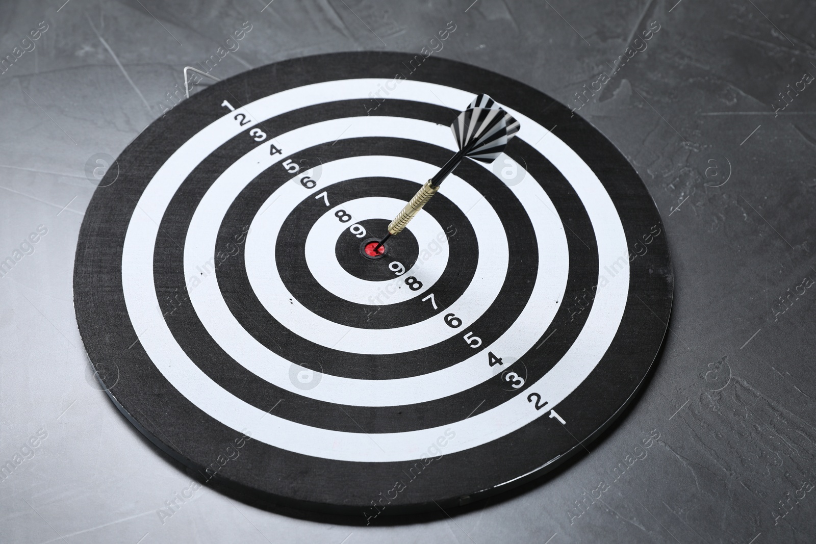 Targeting. Dart board with arrow on gray textured background Photo of Targeting. Dart board with arrow on gray textured background