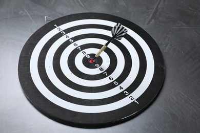 Photo of Targeting. Dart board with arrow on gray textured background