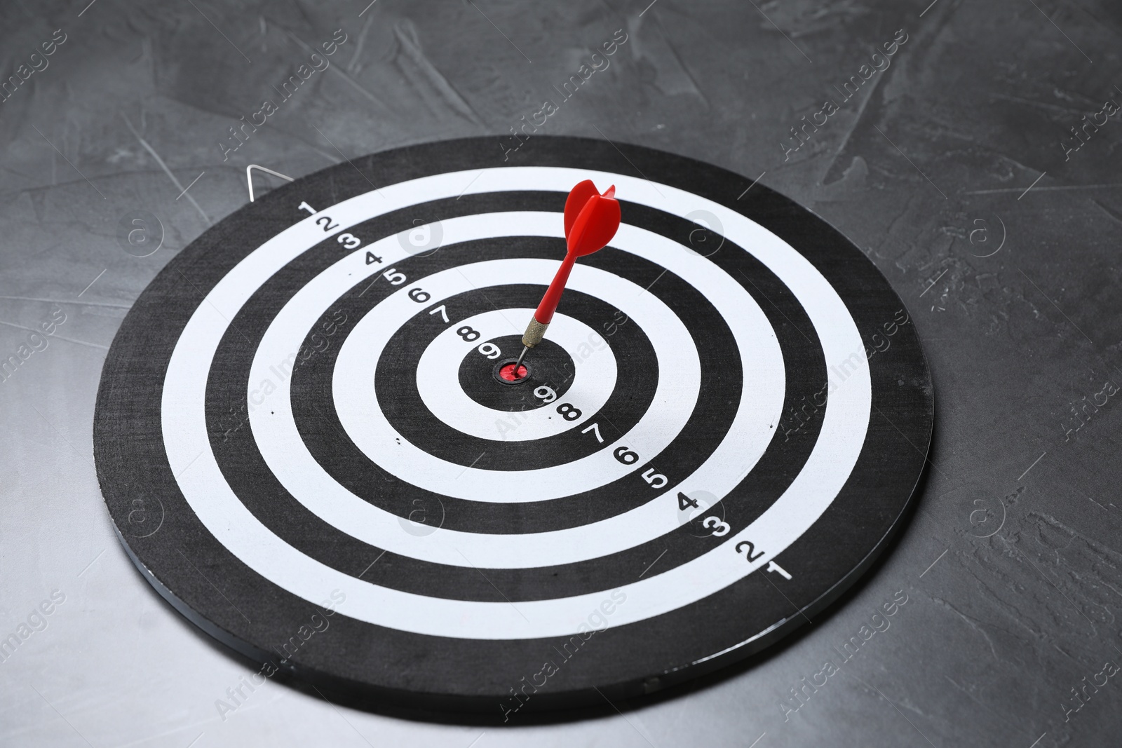 Targeting. Dart board with arrow on gray textured background Photo of Targeting. Dart board with arrow on gray textured background