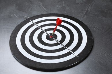 Photo of Targeting. Dart board with arrow on gray textured background