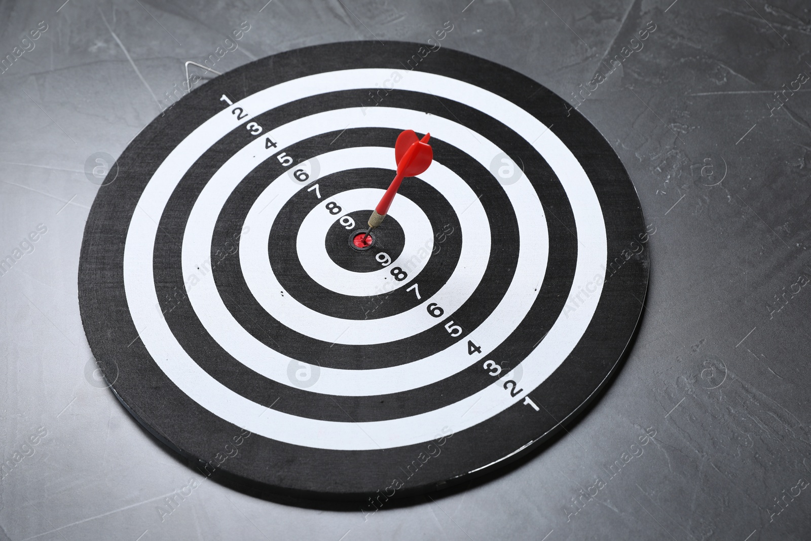 Targeting. Dart board with arrow on gray textured background Photo of Targeting. Dart board with arrow on gray textured background