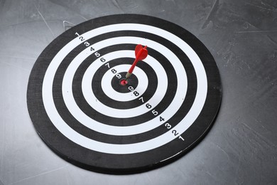 Photo of Targeting. Dart board with arrow on gray textured background
