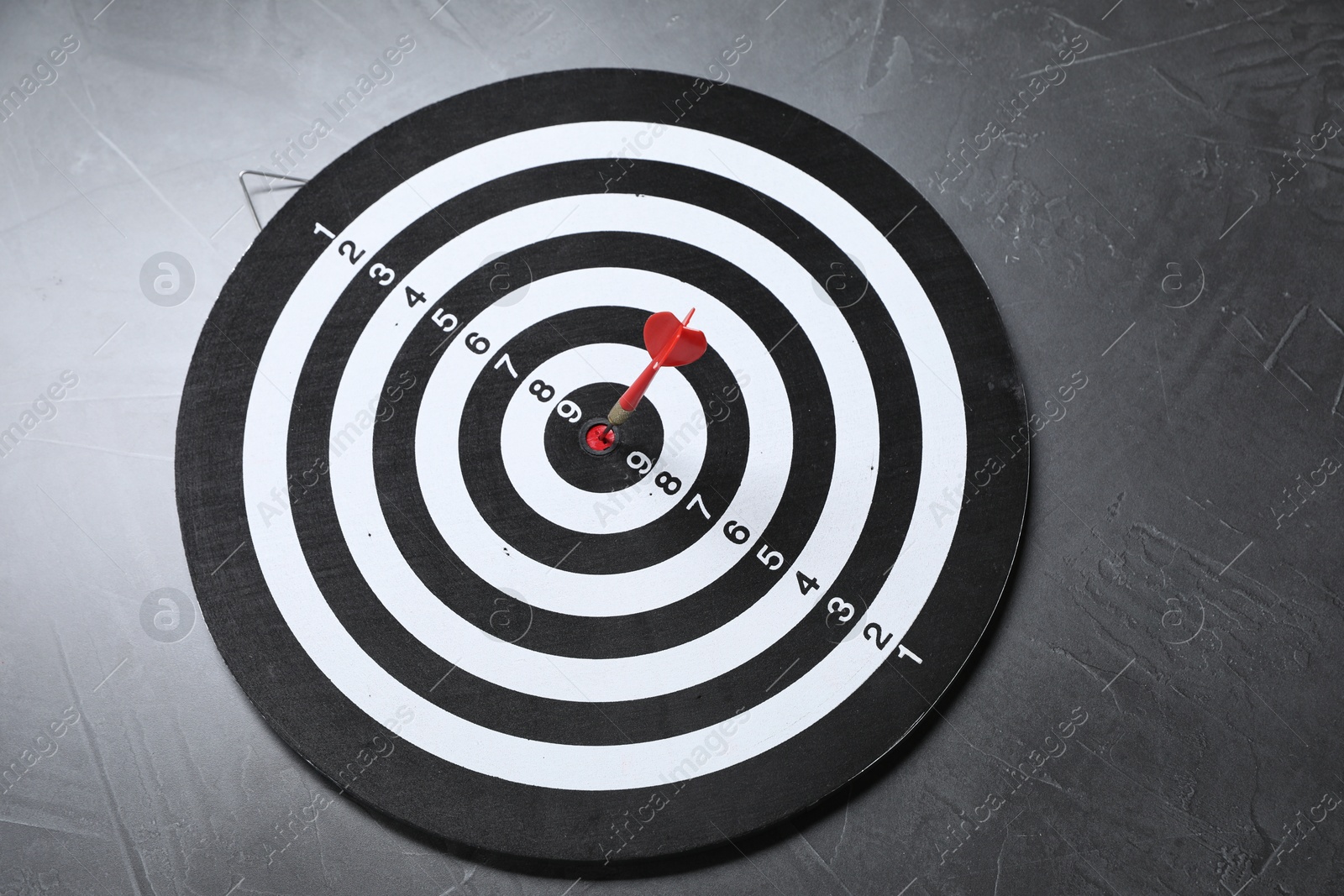 Targeting. Dart board with arrow on gray textured background, above view Photo of Targeting. Dart board with arrow on gray textured background, above view