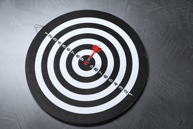 Photo of Targeting. Dart board with arrow on gray textured background, above view
