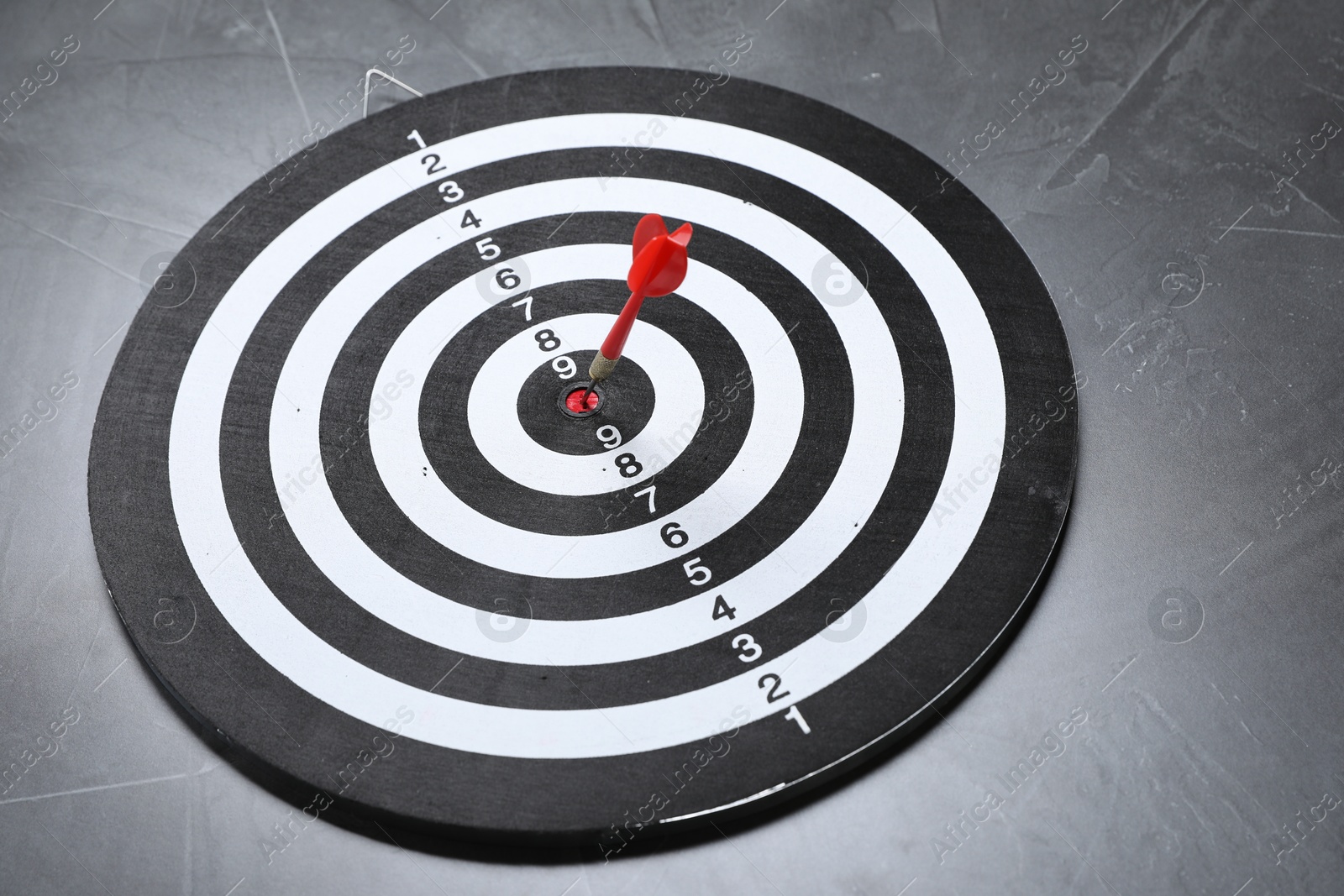 Targeting. Dart board with arrow on gray textured background Photo of Targeting. Dart board with arrow on gray textured background