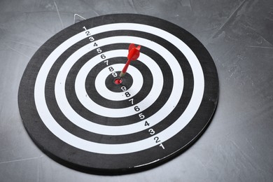 Photo of Targeting. Dart board with arrow on gray textured background