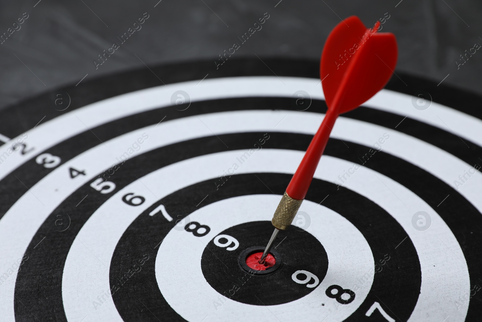 Targeting. Dart board with arrow on gray background, closeup Photo of Targeting. Dart board with arrow on gray background, closeup