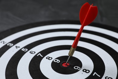 Photo of Targeting. Dart board with arrow on gray background, closeup