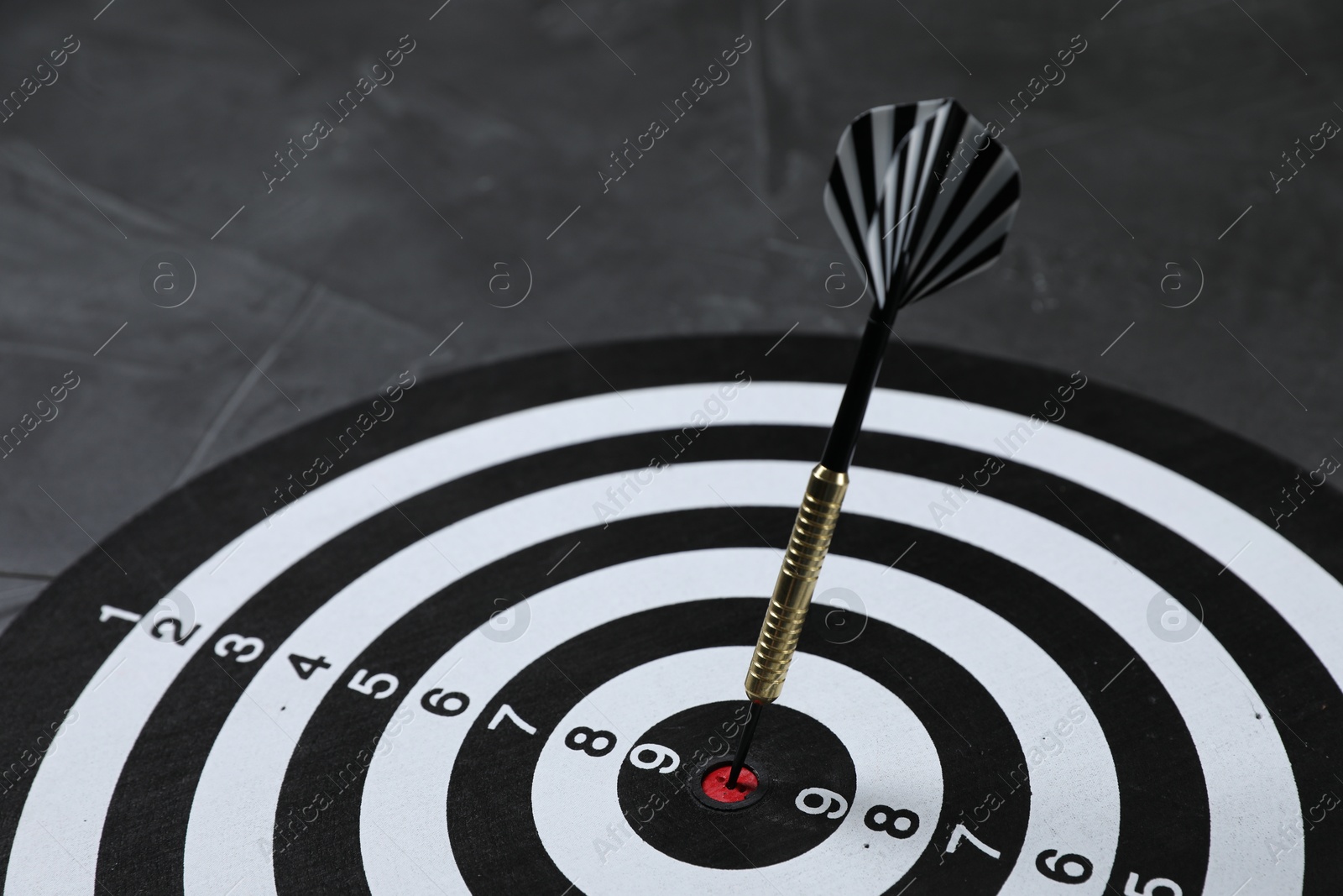 Targeting. Dart board with arrow on gray background, closeup Photo of Targeting. Dart board with arrow on gray background, closeup