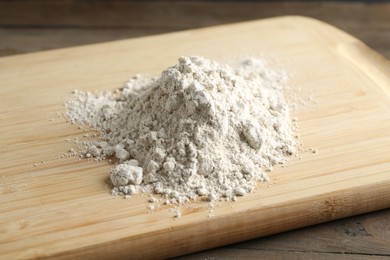 Photo of Pile of flour on wooden table, closeup