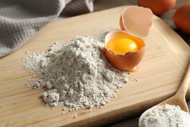 Photo of Pile of flour and broken egg on table, closeup