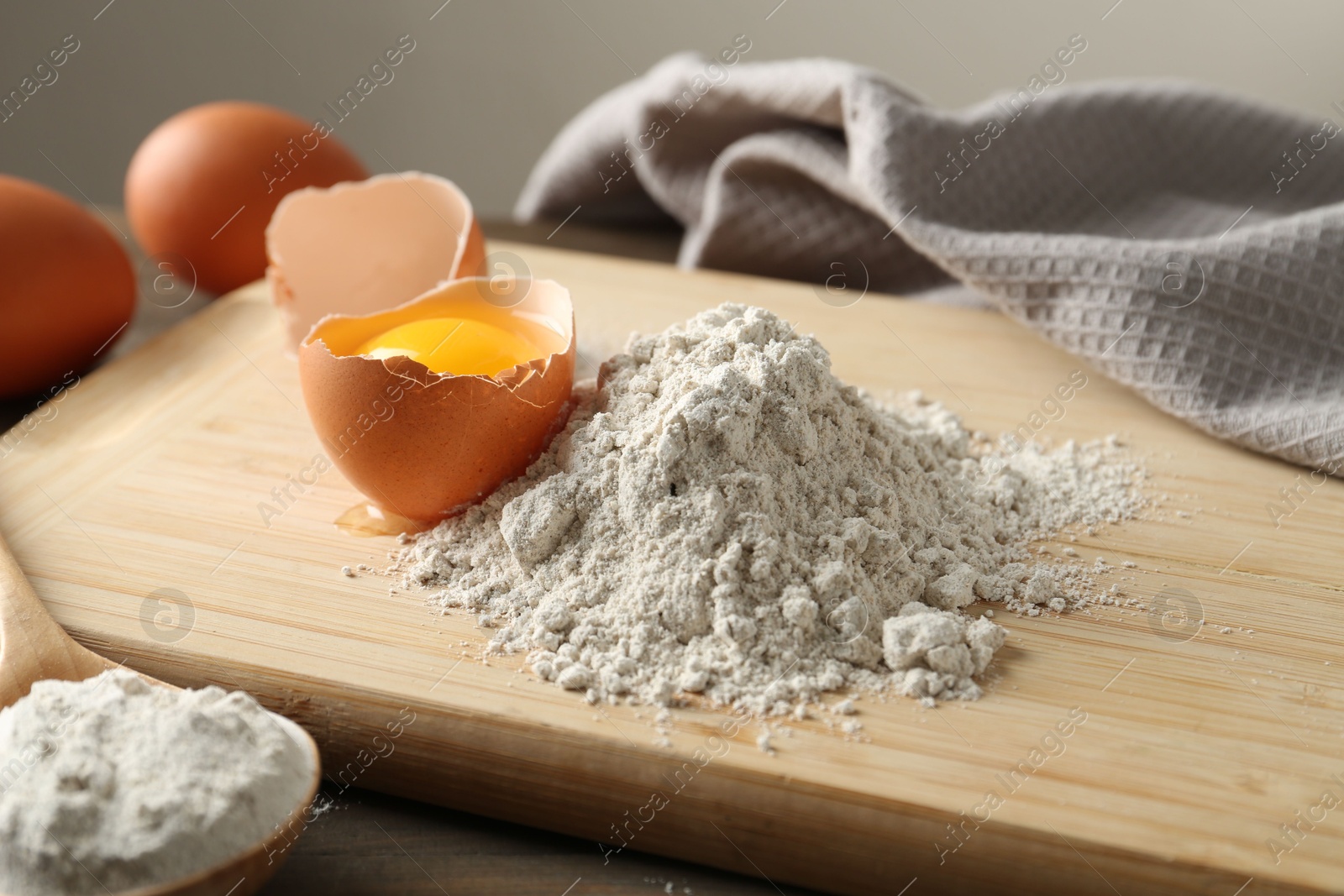 Pile of flour and broken egg on wooden table against grey background, closeup Photo of Pile of flour and broken egg on wooden table against grey background, closeup