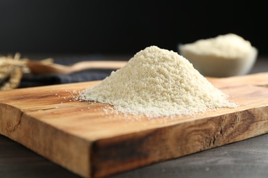 Photo of Pile of flour on dark wooden table against black background, closeup