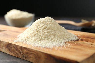 Photo of Pile of flour on dark wooden table against black background, closeup