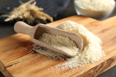 Photo of Pile of flour and scoop on dark wooden table, closeup