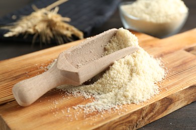 Photo of Pile of flour and scoop on dark wooden table, closeup