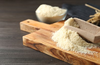 Photo of Pile of flour and scoop on dark wooden table, closeup