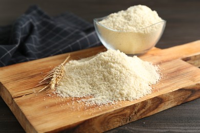 Photo of Pile of flour and spike on dark wooden table, closeup