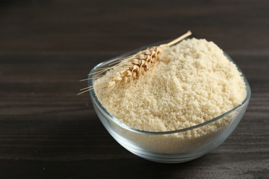 Photo of Flour and spike in bowl on dark wooden table, closeup