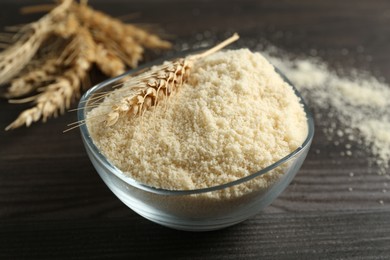 Photo of Flour and spike in bowl on dark wooden table, closeup