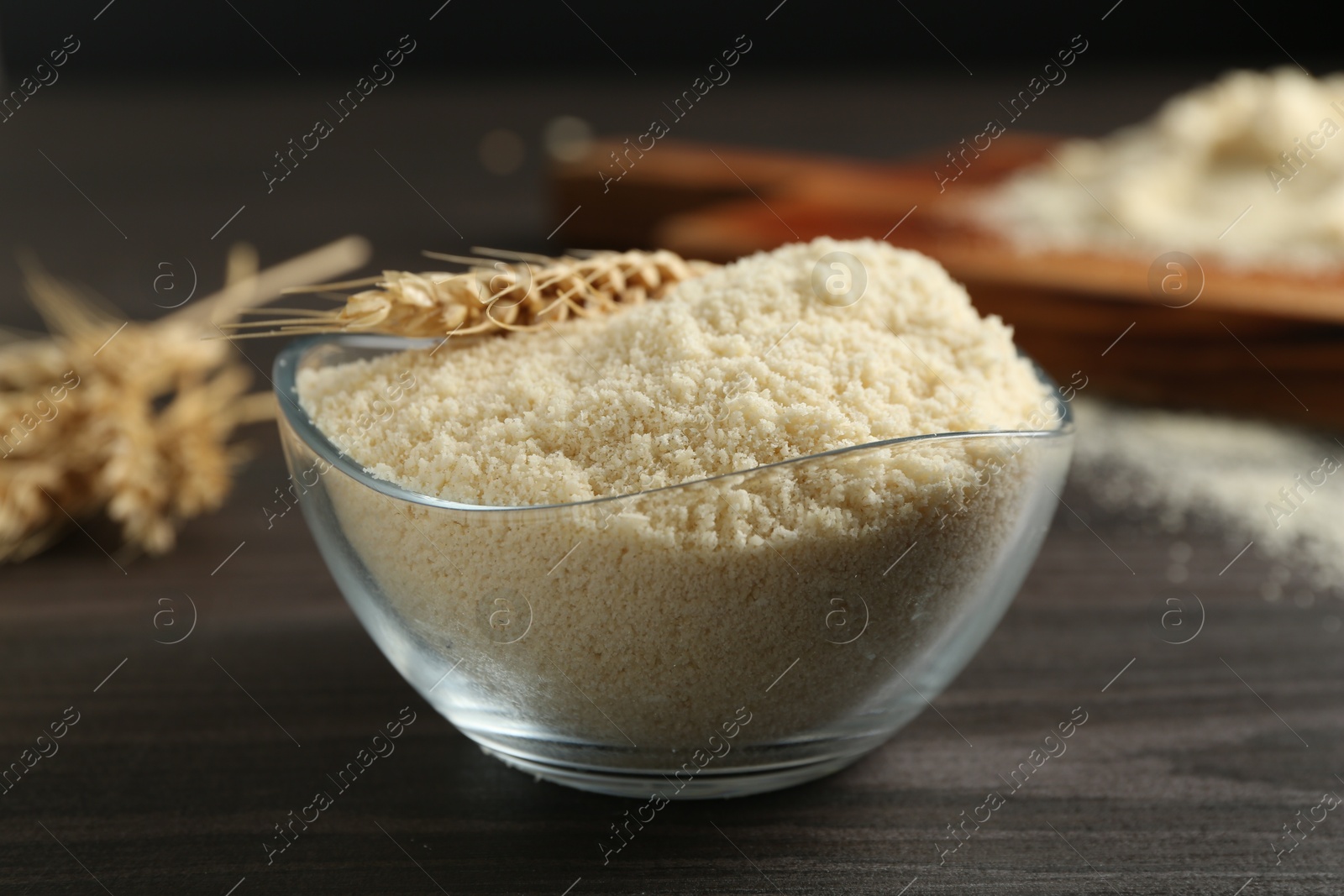 Photo of Flour and spike in bowl on dark wooden table, closeup