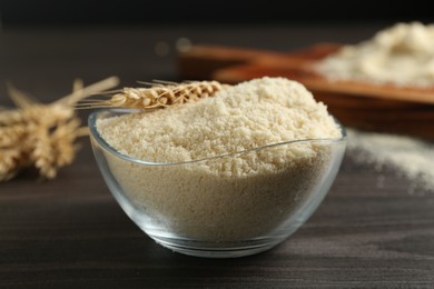 Photo of Flour and spike in bowl on dark wooden table, closeup