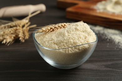 Photo of Flour and spike in bowl on dark wooden table, closeup