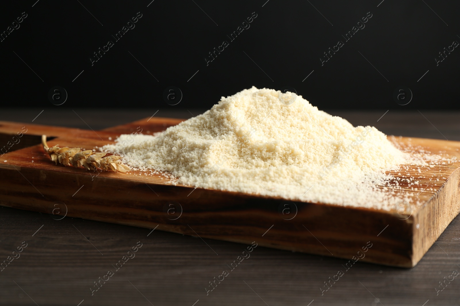 Pile of flour and spike on dark wooden table against black background, closeup Photo of Pile of flour and spike on dark wooden table against black background, closeup