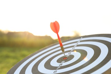 Photo of Targeting. Dart board with arrow outdoors, closeup