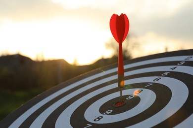 Photo of Targeting. Dart board with arrow outdoors, closeup