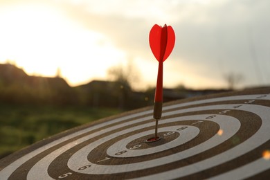 Photo of Targeting. Dart board with arrow outdoors, closeup