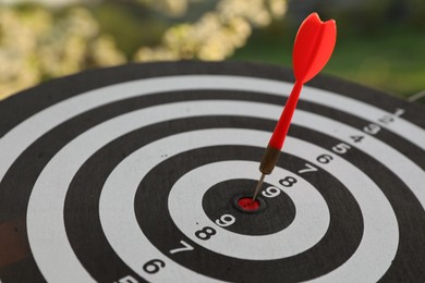 Photo of Targeting. Dart board with arrow outdoors, closeup