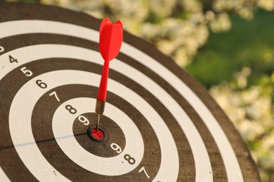 Photo of Targeting. Dart board with arrow outdoors, closeup