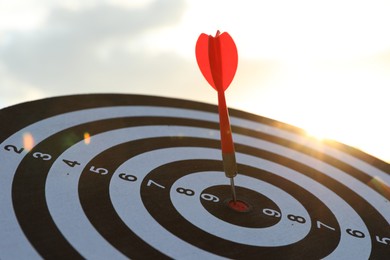 Photo of Targeting. Dart board with arrow outdoors, closeup