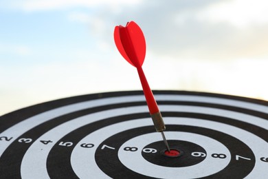 Photo of Targeting. Dart board with arrow outdoors, closeup